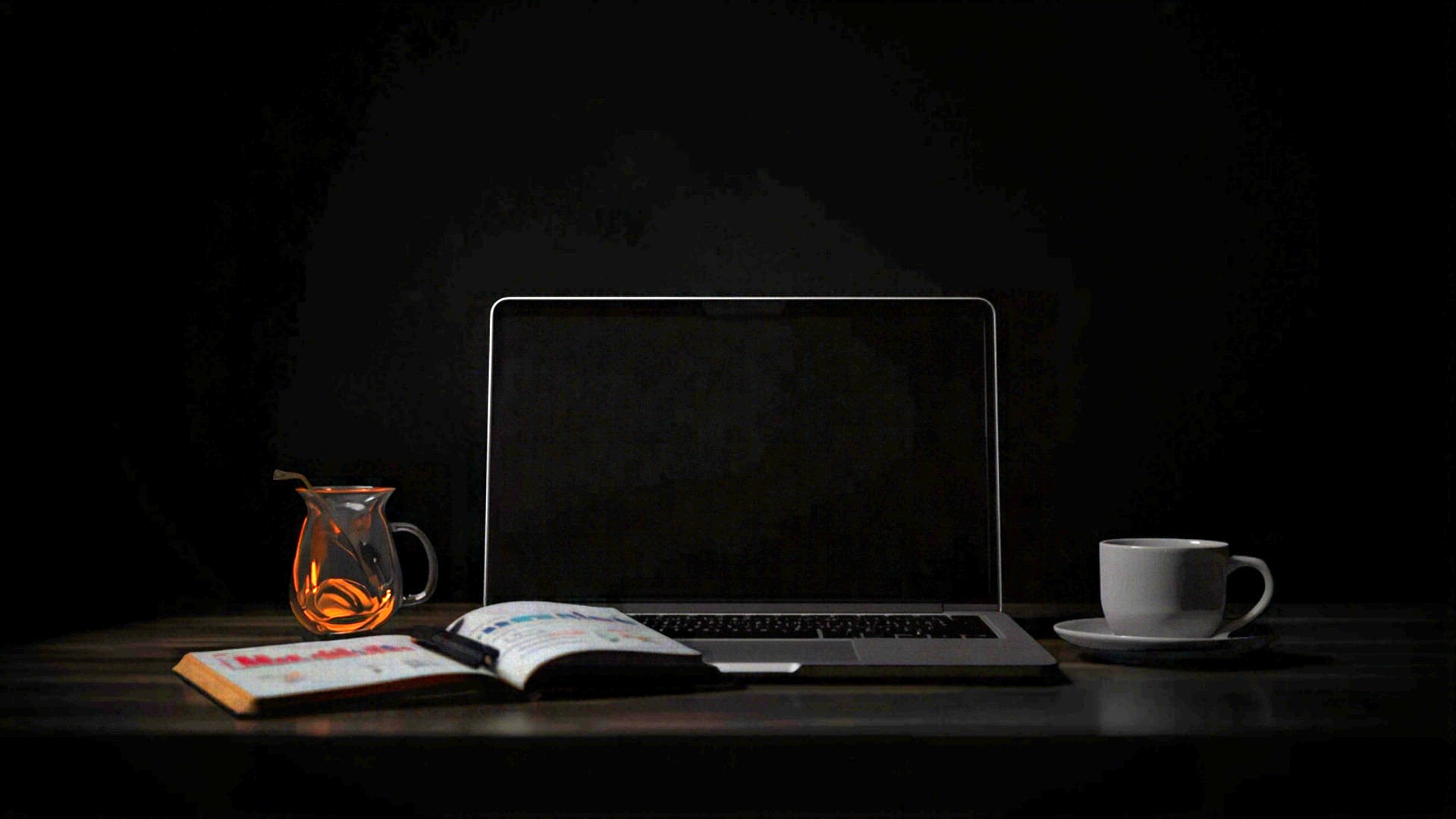 Donkere werkplek met laptop, notitieboek en koffiekop